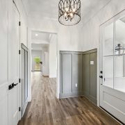 This inviting entryway features elegant wainscoting in a soft green hue, complementing the white walls and door.