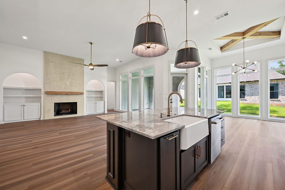 Built-in arched alcoves with cabinetry provide balance and storage while enhancing the room’s architectural interest. Tall ceilings and expansive windows line the right wall, bathing the space in natural light and creating a bright, inviting atmosphere. The layout offers effortless flow for everyday living and entertaining, blending luxury finishes with open, modern comfort.