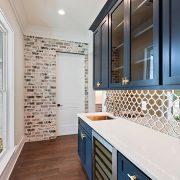 This beautiful well appointed butler's pantry with a nice mirrored custom backsplash and dark custom cabinets.