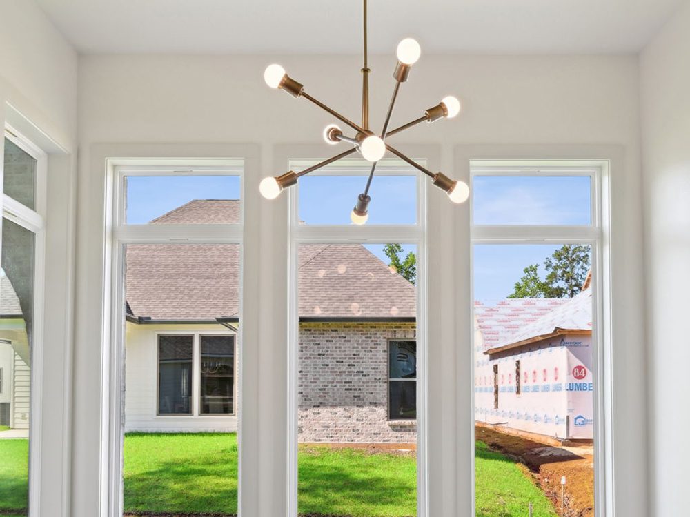 This close-up view showcases a striking sputnik-style chandelier, the centerpiece of a modern dining nook or breakfast area. Suspended at eye level, the fixture features sleek, angular arms and globe bulbs, casting soft, even light throughout the space. The brushed gold finish adds a touch of contemporary elegance.