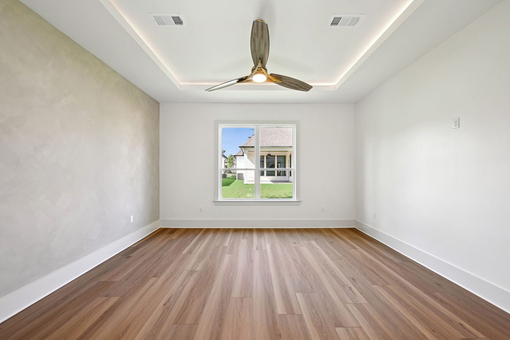 This inviting bedroom offers a peaceful retreat defined by clean lines and natural textures. The room features warm wood-look flooring and a soothing neutral palette, with one accent wall finished in a subtle plaster-style texture for added depth and softness.