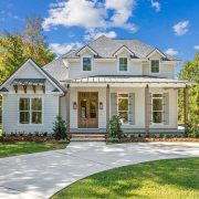 A charming curved driveway frames the lush green lawn and professional landscaping, offering a graceful approach to this idyllic and timeless residence nestled among mature trees.