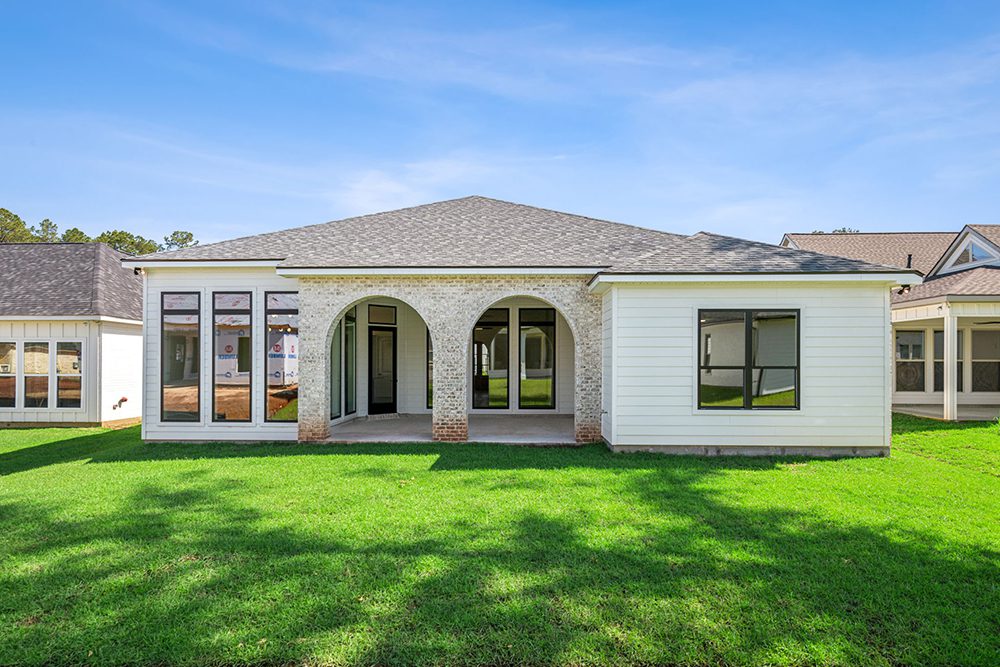 Set against a lush green lawn and framed by neighboring new builds, this backyard view perfectly balances privacy, comfort, and architectural appeal.