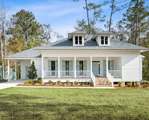 The landscaped front yard is neatly bordered with fresh greenery and mulch, leading up to a classic brick staircase entry. Nestled on a spacious lot surrounded by mature trees, this home blends classic architectural details with modern charm, offering both beauty and tranquility.