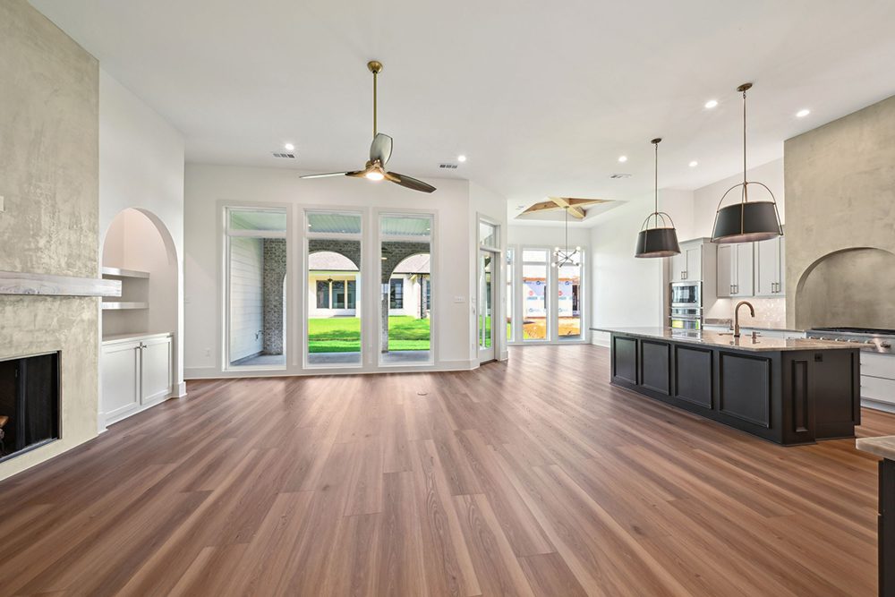 The kitchen showcases a bold contrast with black cabinetry on the island, paired with modern pendant lighting and a dramatic hood set into a textured accent wall.
