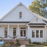 Dormer windows and a metal awning add architectural interest. Lush landscaping surrounds the front path, and a sign confirms this inviting home is already sold.